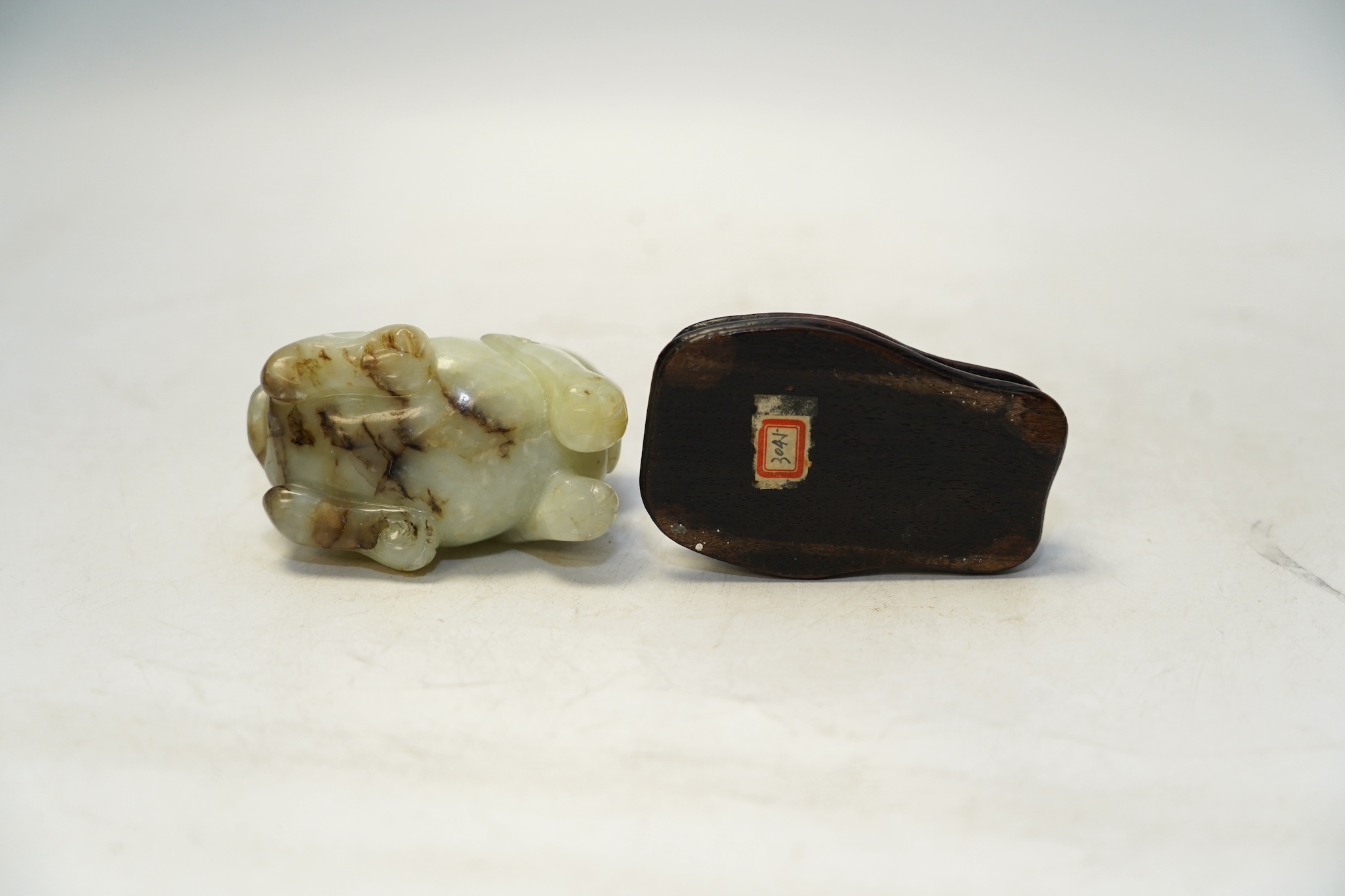 A Chinese carved jade ‘lion dog’ and stand, 8cm tall. Condition fair to good.